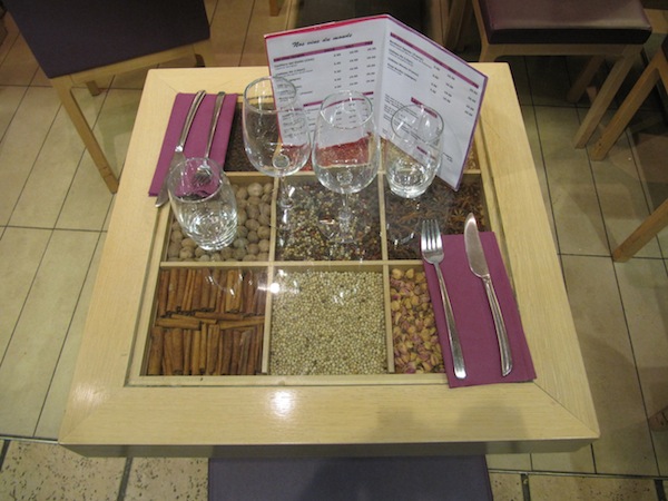 A vendor has beautiful tables with spices enclosed behind a glass surface