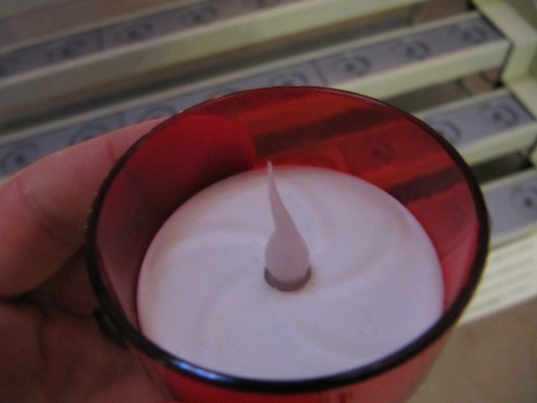 Top of an electric votive candle; the light flickers within the flame mould.