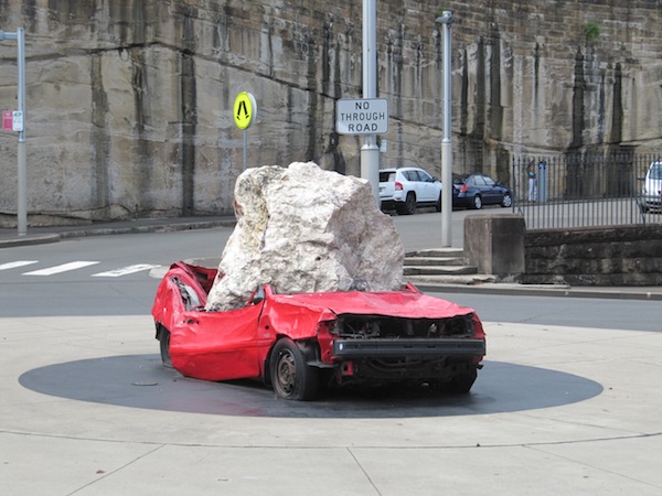 Sculpture of a car crushed by a rock