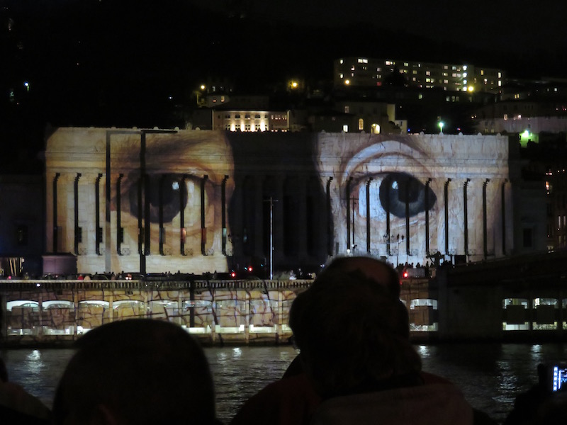 Eyes of well known artwork illuminate the buildings.