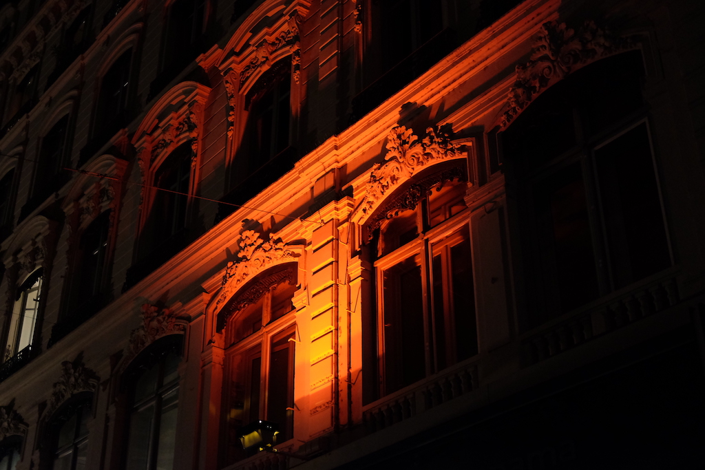 Red light illuminates a street wall in Lyon.
