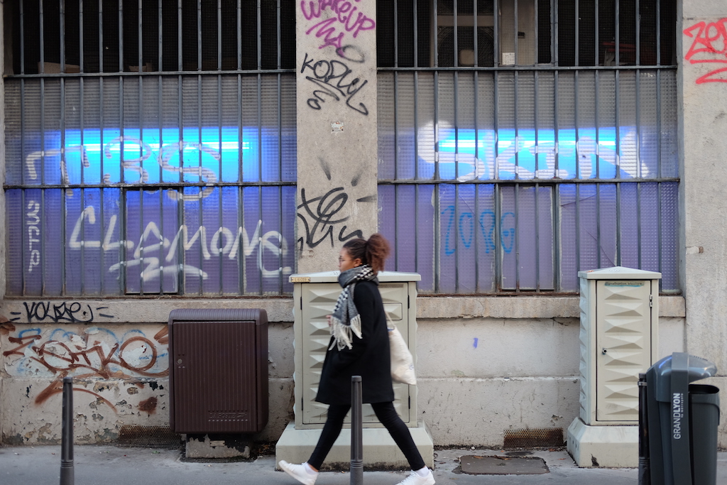 Woman walking near graffiti in 6ème, Lyon